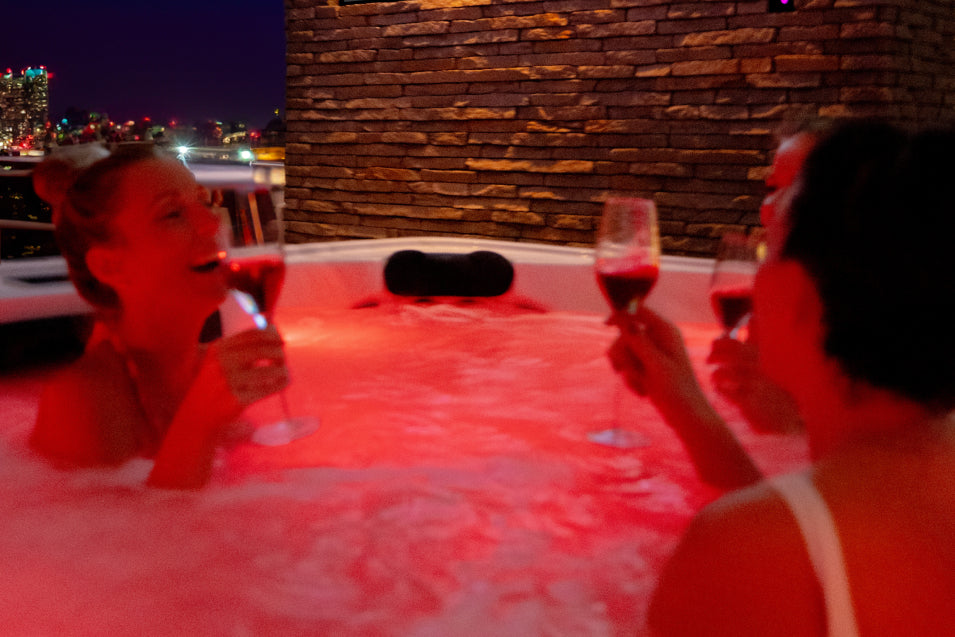 Women drinking wine in the evening in the hot tub.