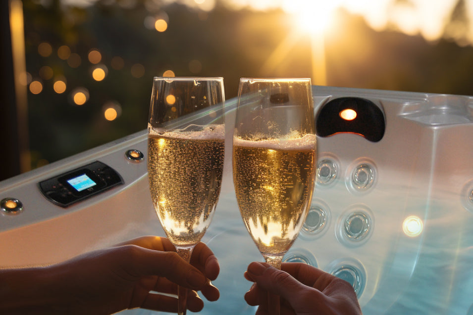 Couple toasting champagne glasses next to their hot tub, sunlight shining in the sky.
