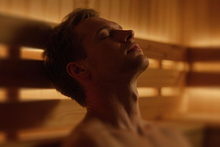 Person lying down in a warm wooden sauna