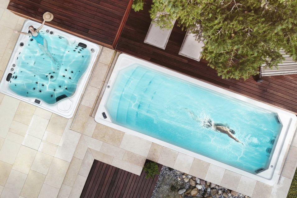 Bird-eye view of a swimmer in a swim spa and a woman enjoying a hot tub.